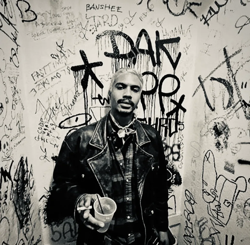 Portrait of Mathieu against a graffiti-covered wall