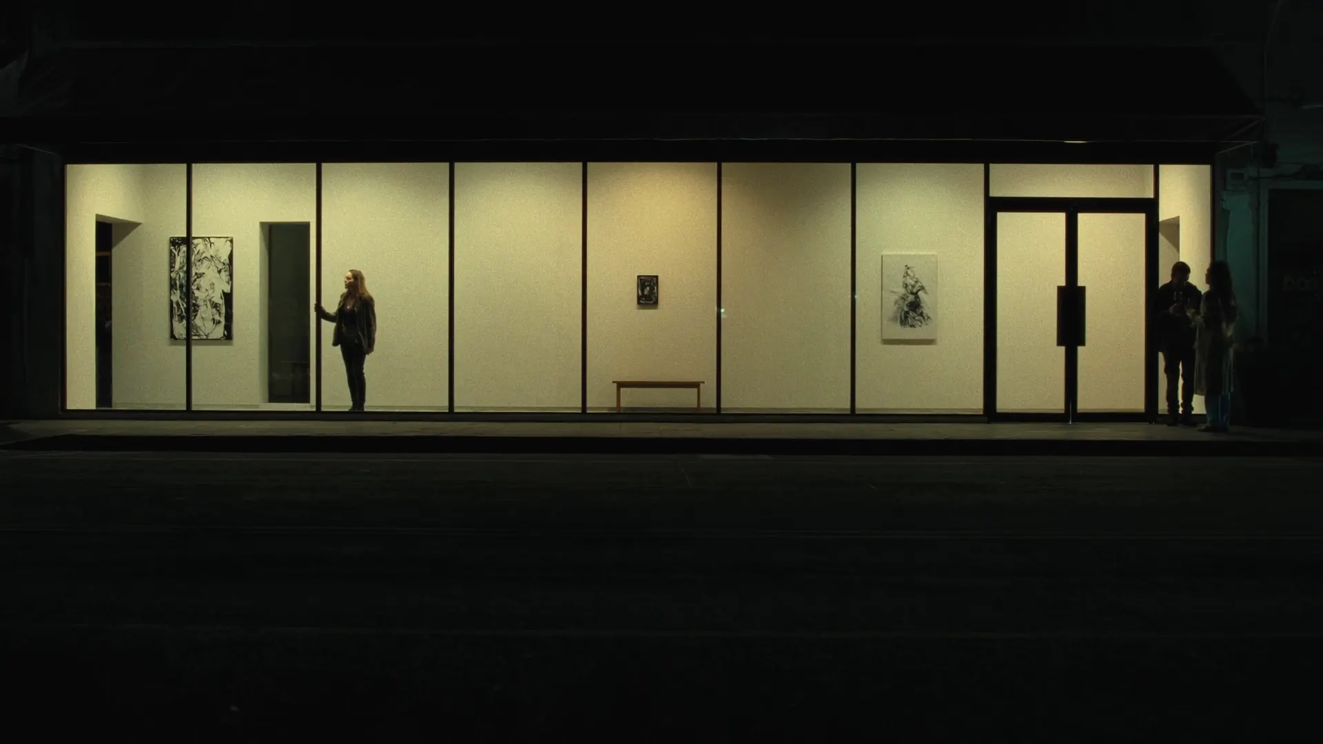 Gallery opening at night seen through glass